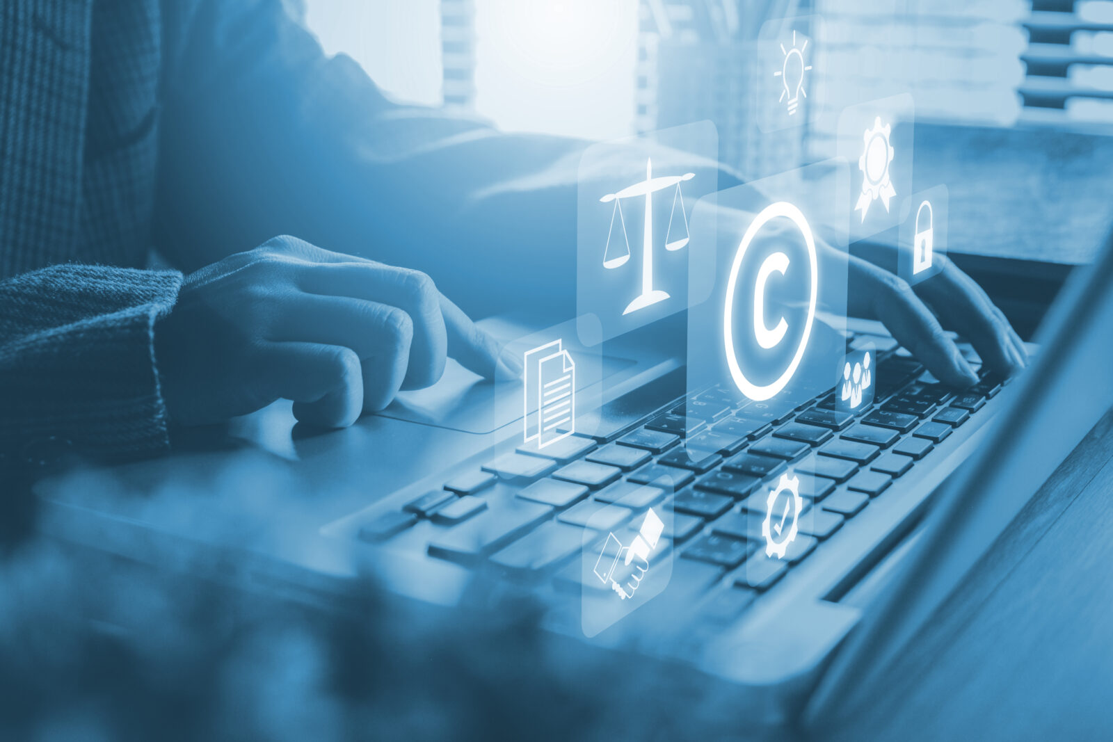 Hands using a laptop with virtual screen showing copyright or patent symbols