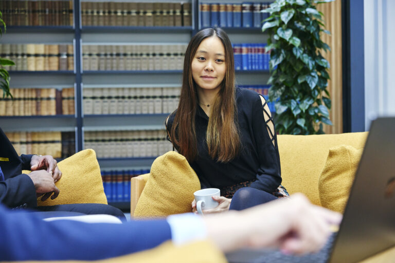 woman holding a coffee cup sat on an office sofa