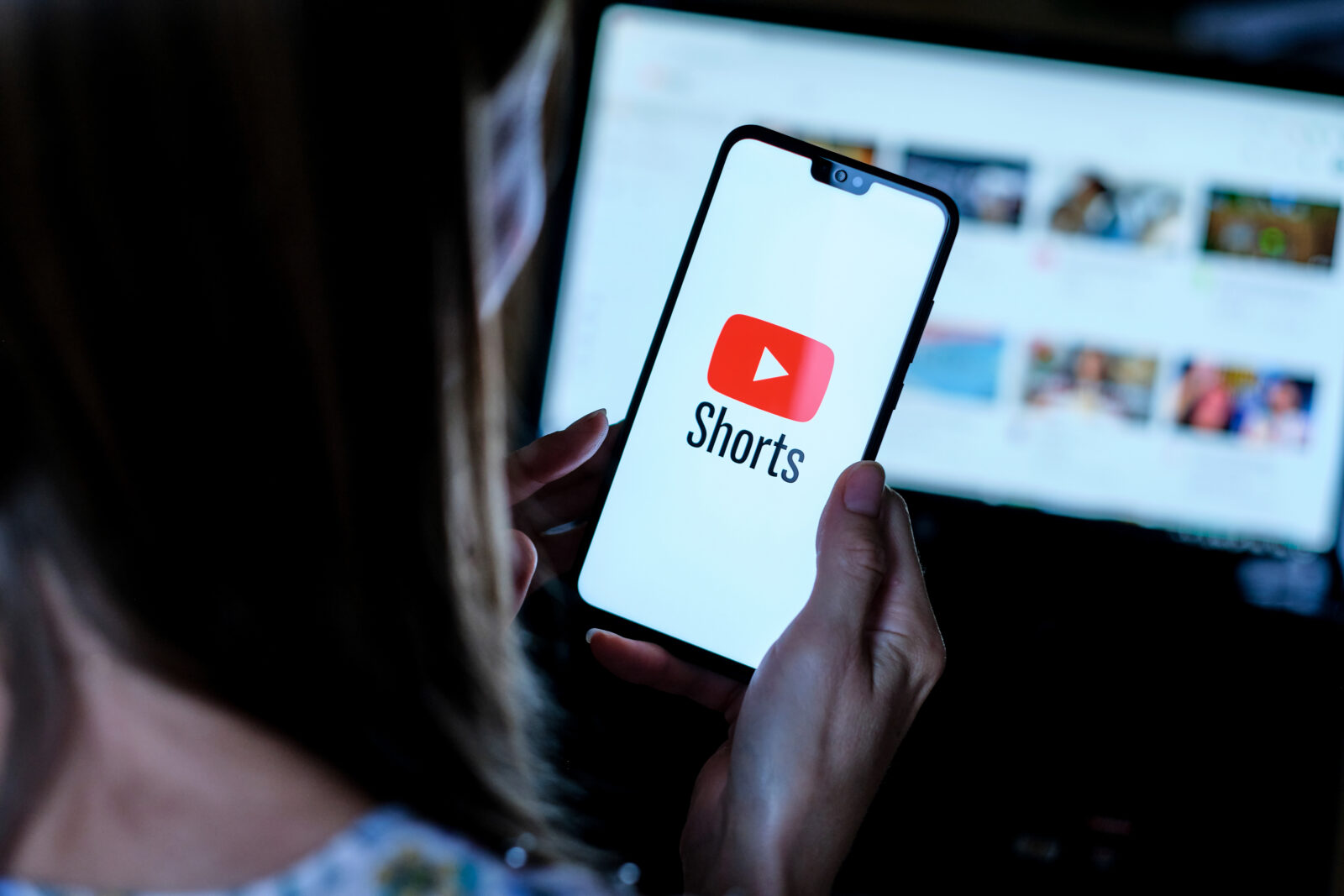 Youtube Shorts app logo seen on the smartphone held by girl