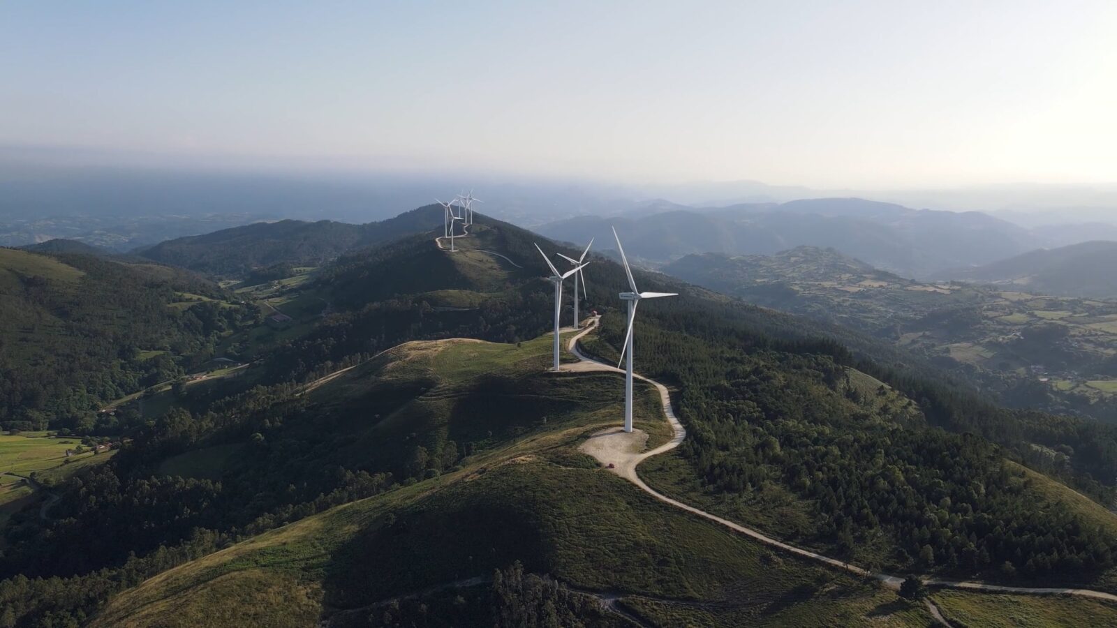 wide shot of wind turbines on a green mountain top