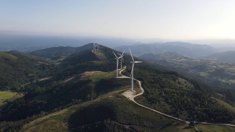 wide shot of wind turbines on a green mountain top