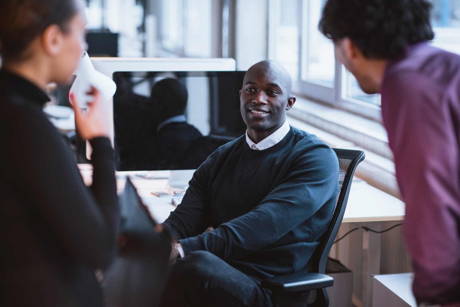Meeting at work with three people in relaxed setting
