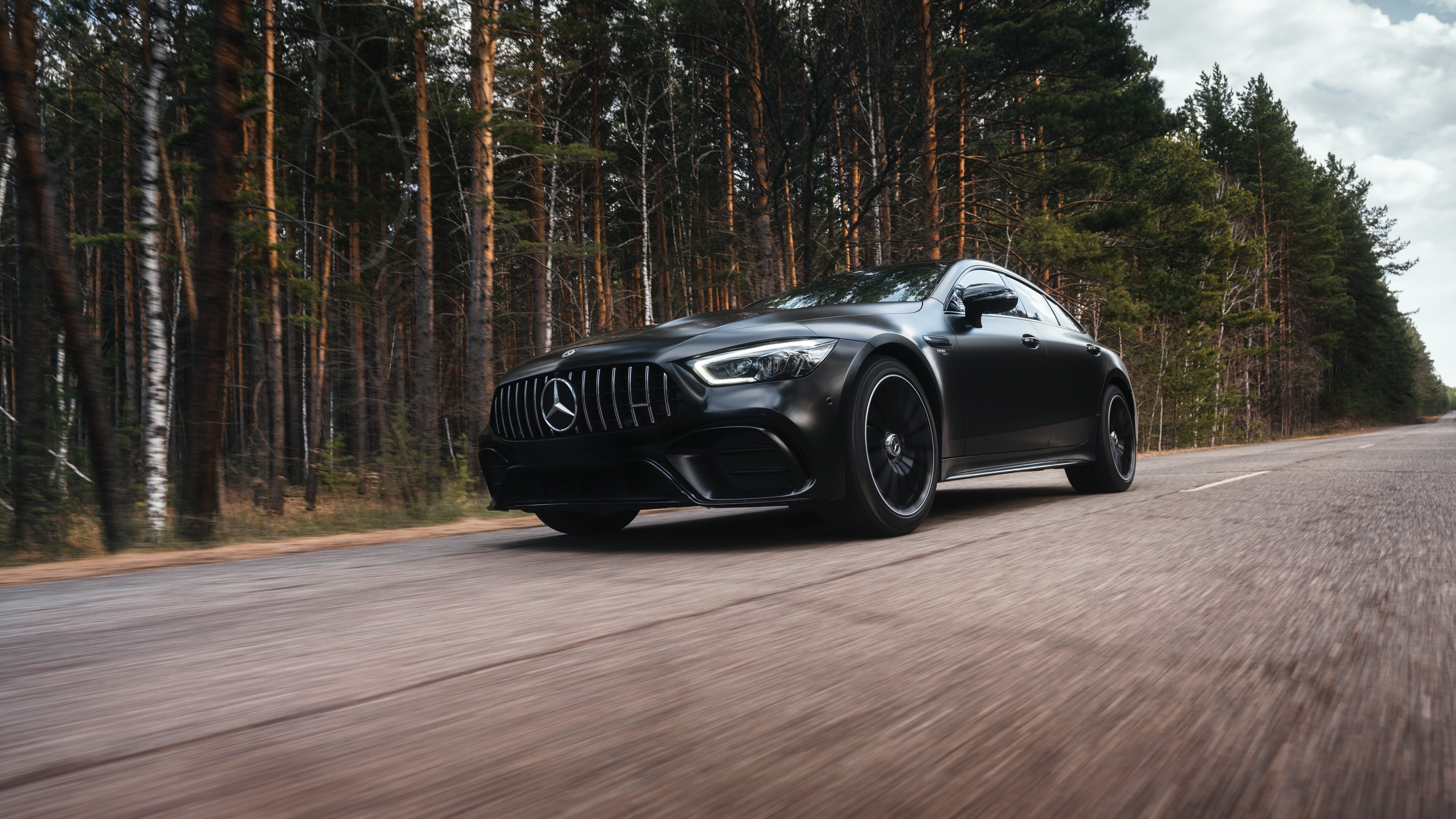 Matte black Mercedes-Benz AMG GT 43 moving along a highway in the forest