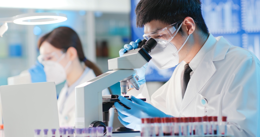 A medical worker looking into microscope in lab