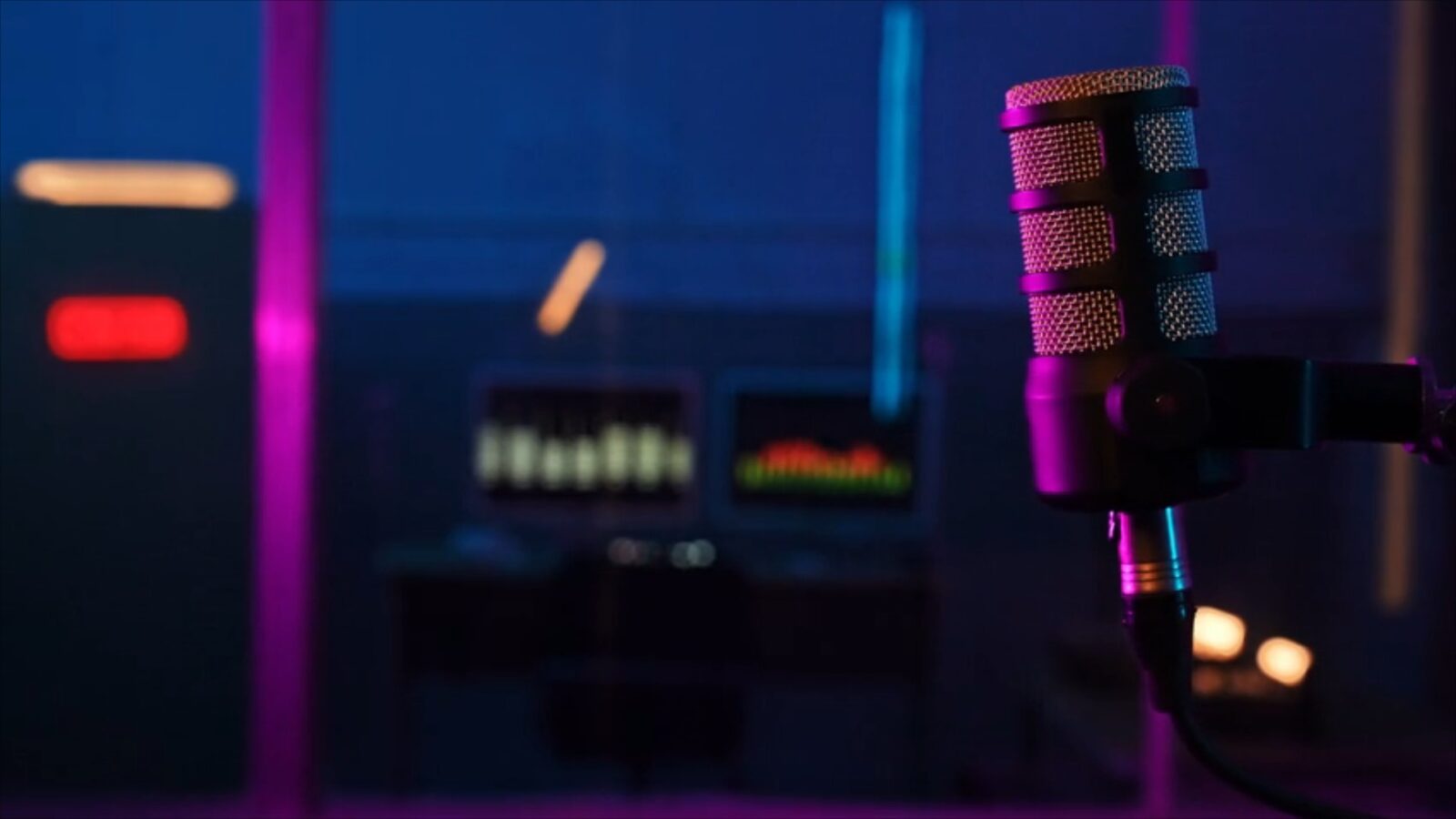 Image of a recording microphone, with audio equipment in the background in a studio setting