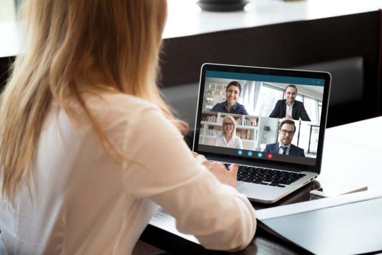 Woman at a desk on a laptop during a video call with four participants