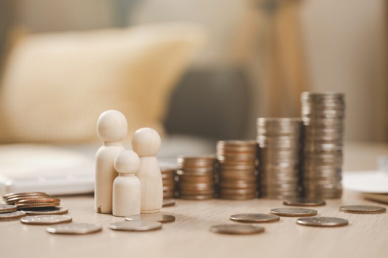 Wooden family figurines with a pile of coins in front