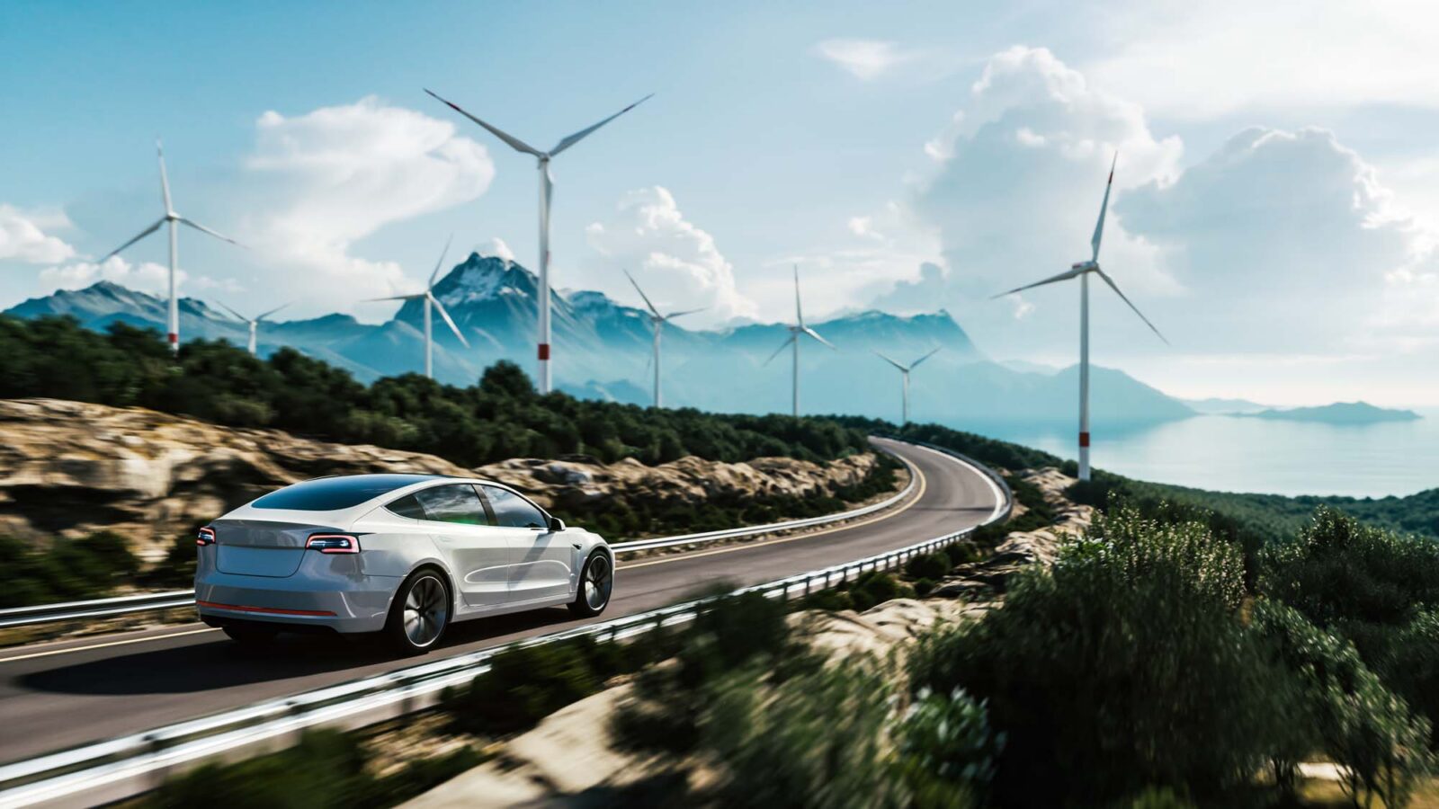 Electric car driving along a winding mountain road with wind turbines in the background
