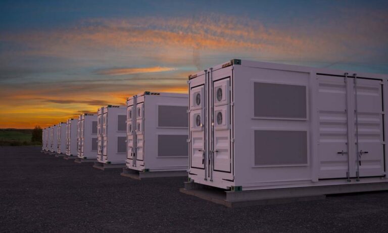 Rows of containerised battery energy storage units on an outdoor site at sunset