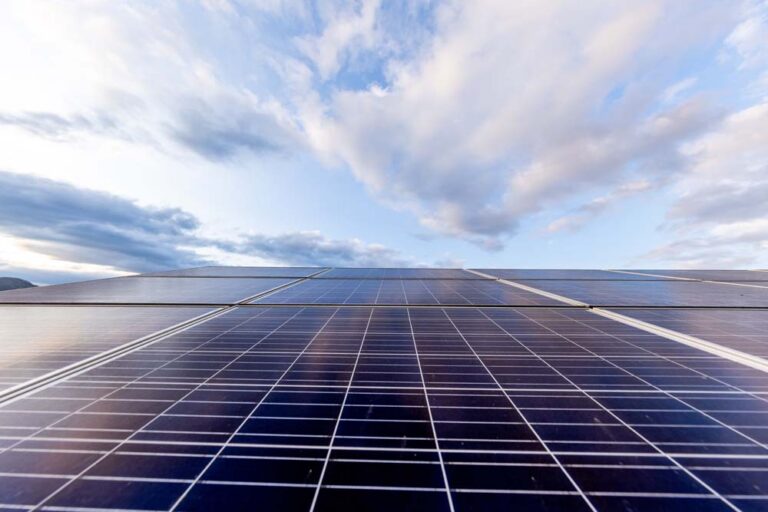 Solar panels beneath a cloudy blue sky